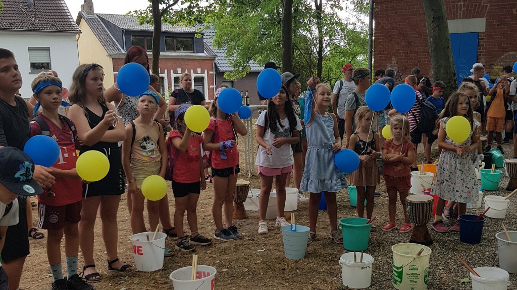 Kinder halten blaue und gelbe Luftballons in den Händen