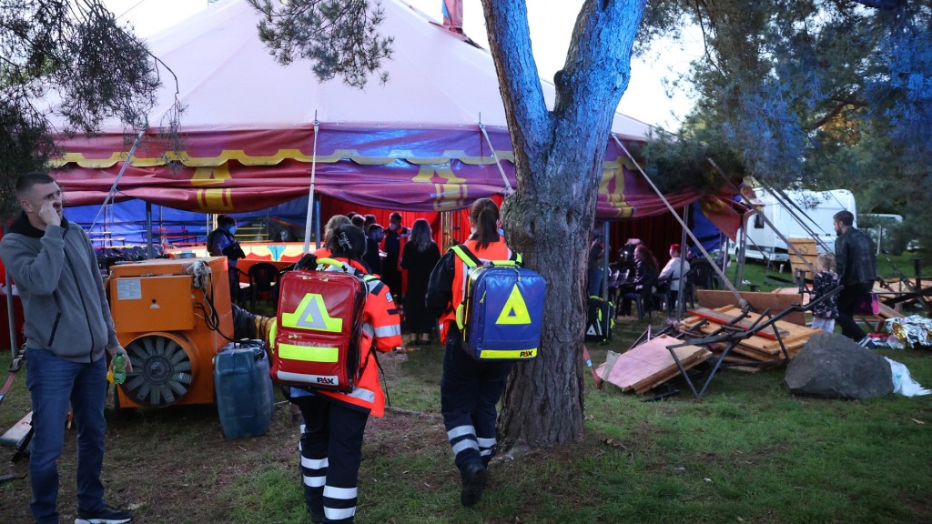 Menschen und Rettungskräfte stehen vor einem Zelt