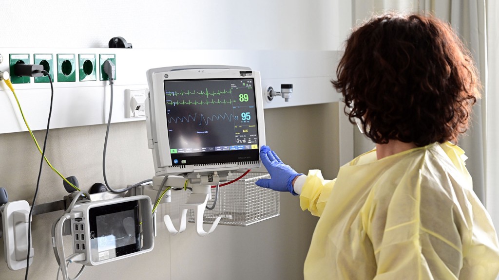 Eine Pflegerin schaut in einem Krankenzimmer auf einen Monitor einer Patientin