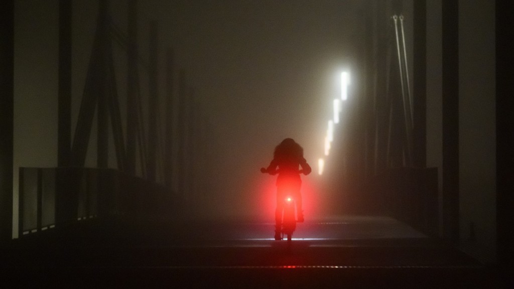 Eine Fahrradfahrerin fährt bei Nebel über eine Brücke.