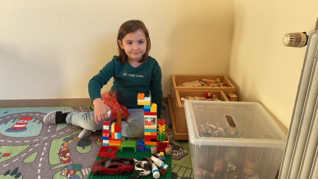 Ein Mädchen spielt auf einem Spielteppich mit Lego