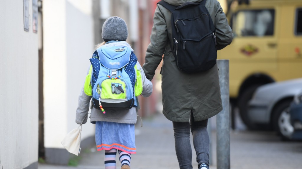 Eine Mutter hält die Hand ihrer Tochter auf dem Weg zur Schule. 