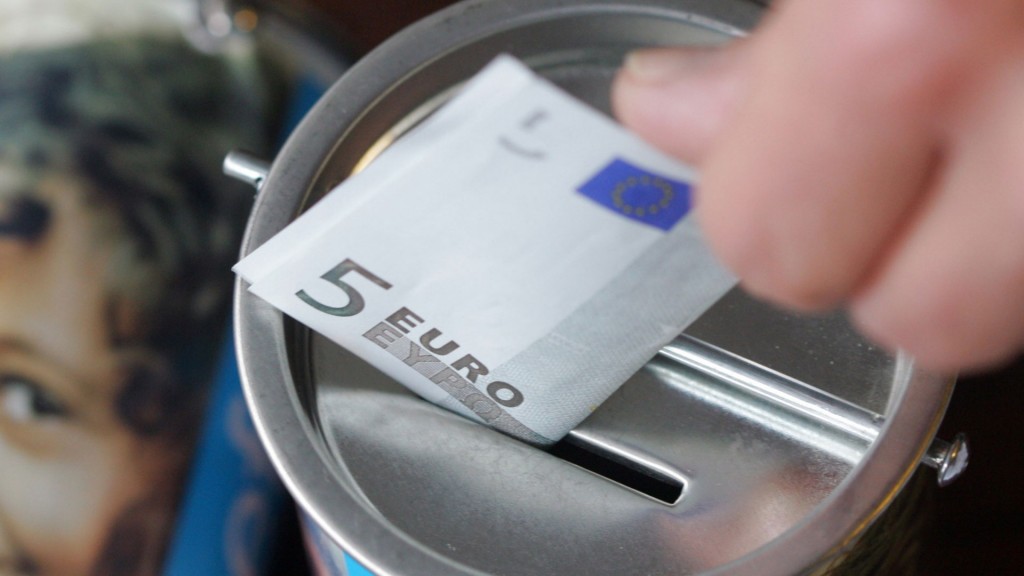 Ein Fünf-Euro-Schein wird in eine Spendendose gesteckt.