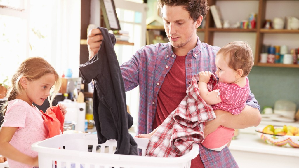 Ein Familienvater kümmert sich um die Wäsche während er ein Kind auf dem Arm hat