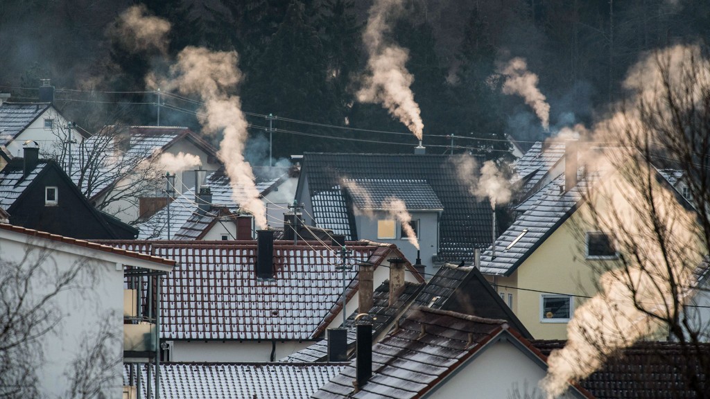 Weißer Dampf steigt bei eisigen Temperaturen aus Schornsteinen von Wohnhäusern