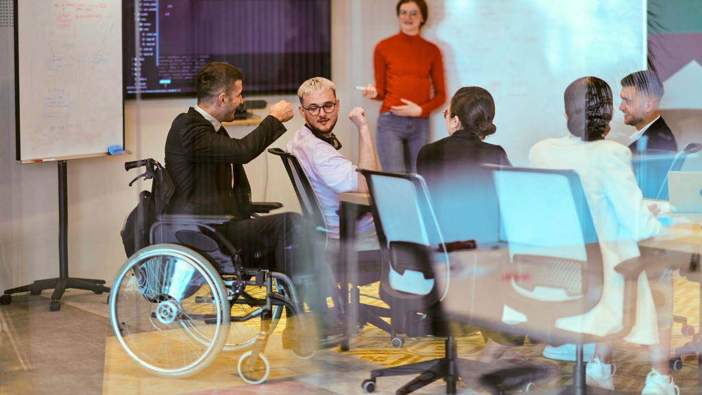 Foto: Ein Rollstuhlfahrer sitzt mit anderen bei einer Besprechung