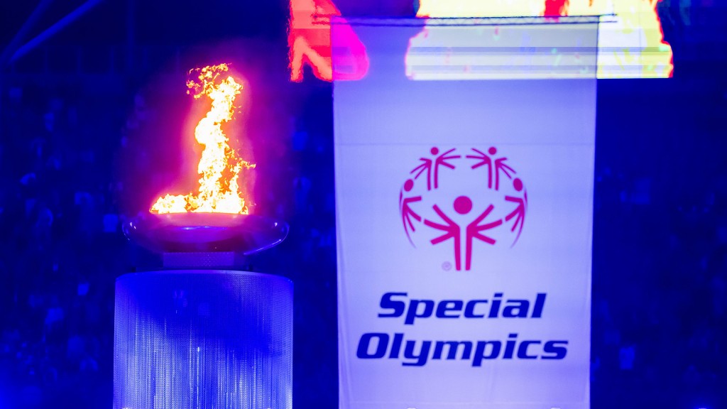 Foto: Das Logo der Special Olympics auf einer Fahne neben der olympischen Flamme.