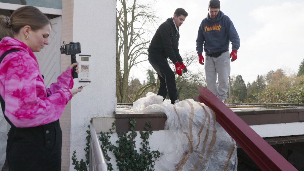 Foto: Frau filmt Männer beim Sanieren eines Hauses.