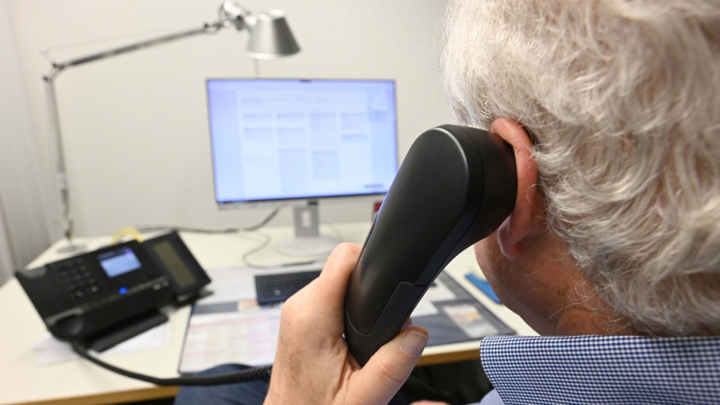 Ein Mitarbeiter sitzt in der Telefonseelsorge und hält einen Telefonhörer an sein Ohr.