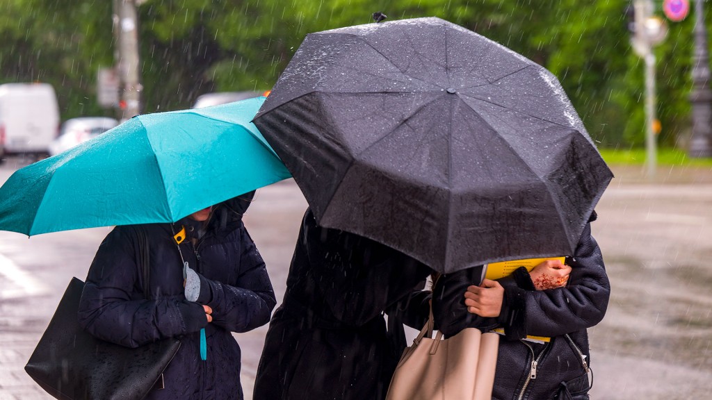 Drei Frauen mit Schirmen bei starkem Regen