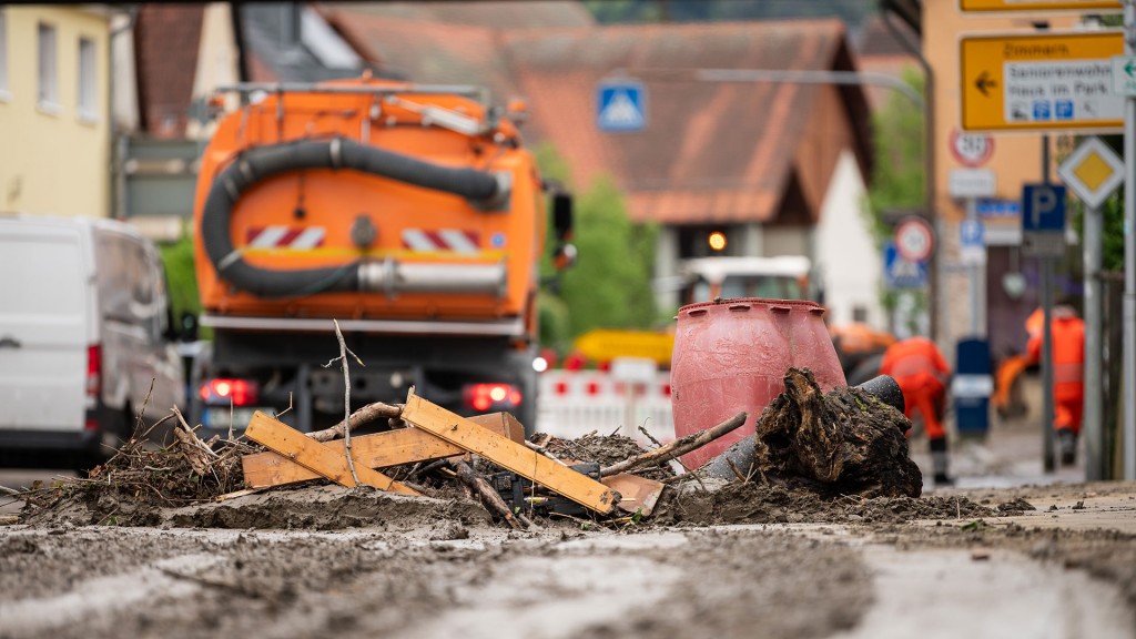 Schutt und Schlammreste des Hochwassers und eine Straßenkehrmaschine