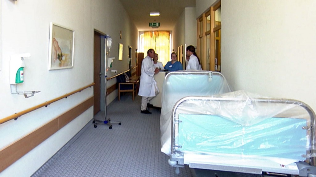 Medizinisches Personal steht neben einem Bett im Krankhausflur in der Merziger Klinik