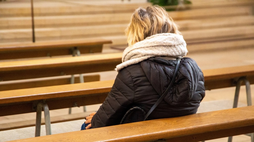 Eine Frau sitzt alleine in einer Kirchenbank.