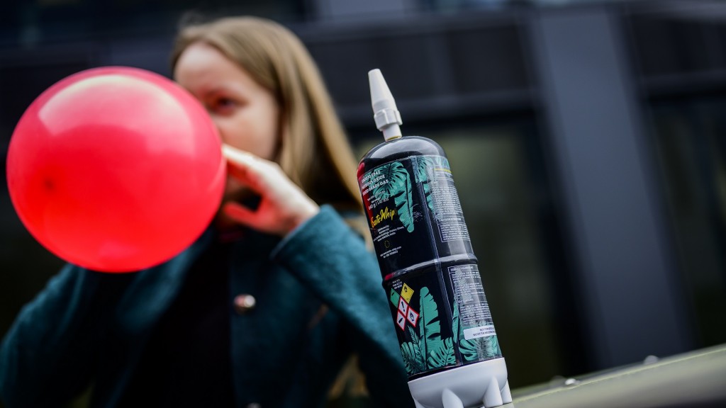 Foto: Eine Frau inhaliert Lachgas aus einem roten Ballon