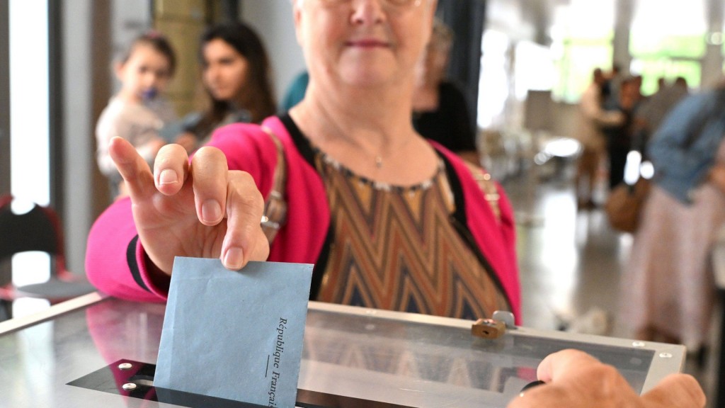 Eine Frau steckt den Wahlumschlag zur Parlamentswahl in die Wahlurne.