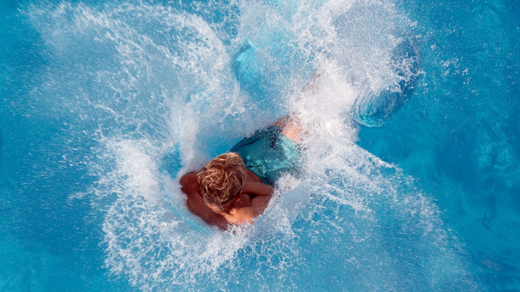 Ein Junge springt im Freibad ins Wasser