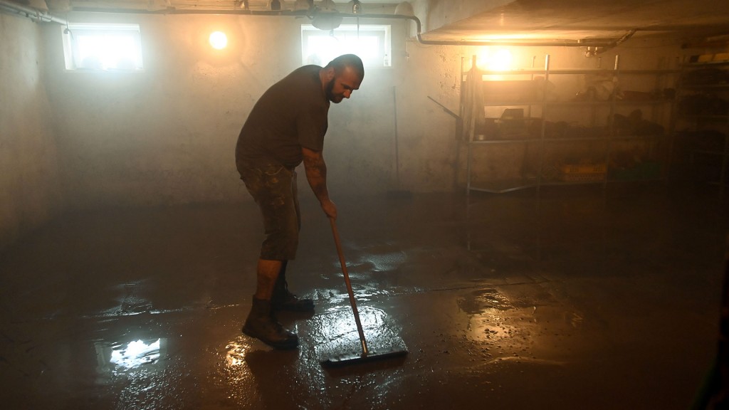 Ein Mann schiebt mit einem Abzieher Wasser aus einem Keller