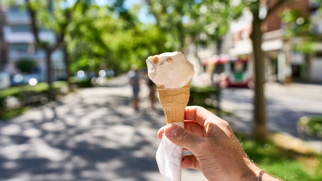 Eine Hand hält ein Eis in einer Waffel an einem sonnigen Sommertag