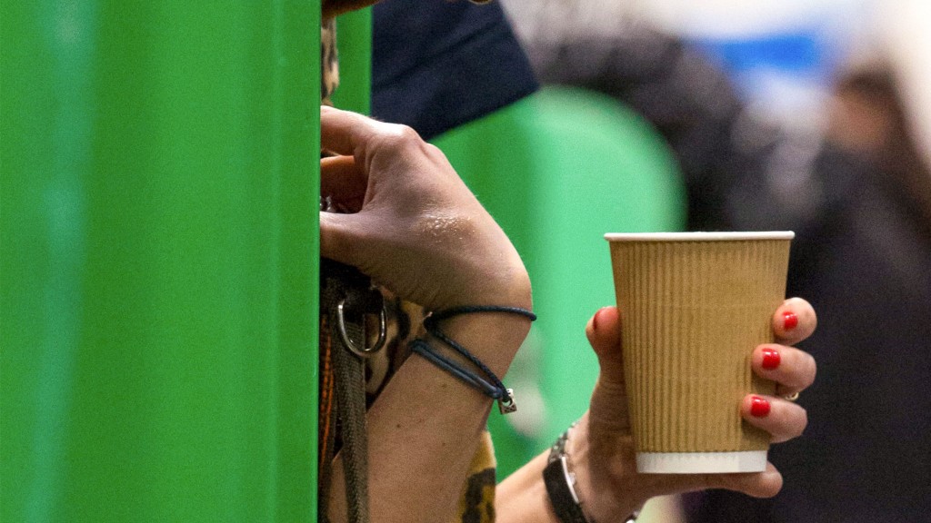 Eine Frau hält einen Getränkebecher aus Pappe in der Hand