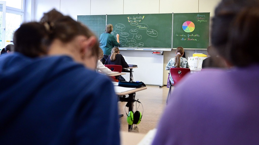 Ein Lehrer schreibt im Unterricht vor der Klasse an die Tafel