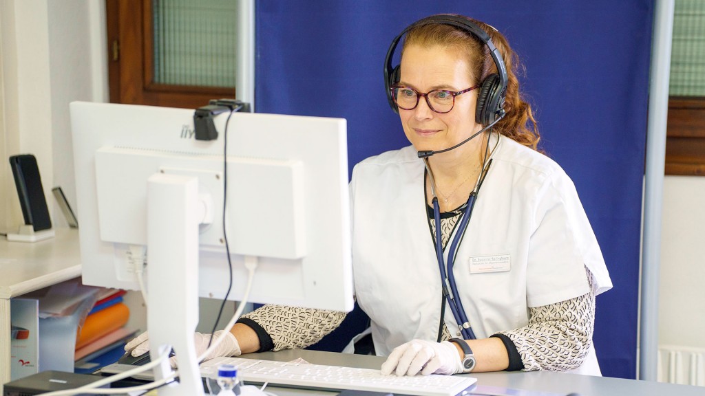 Eine Ärztin sitzt am Computer und telefoniert