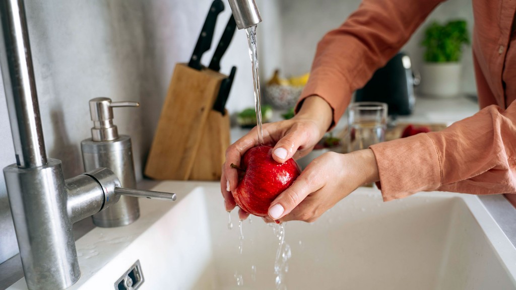 Foto: Jemand wäscht in der Küche einen Apfel mit klarem Wasser ab