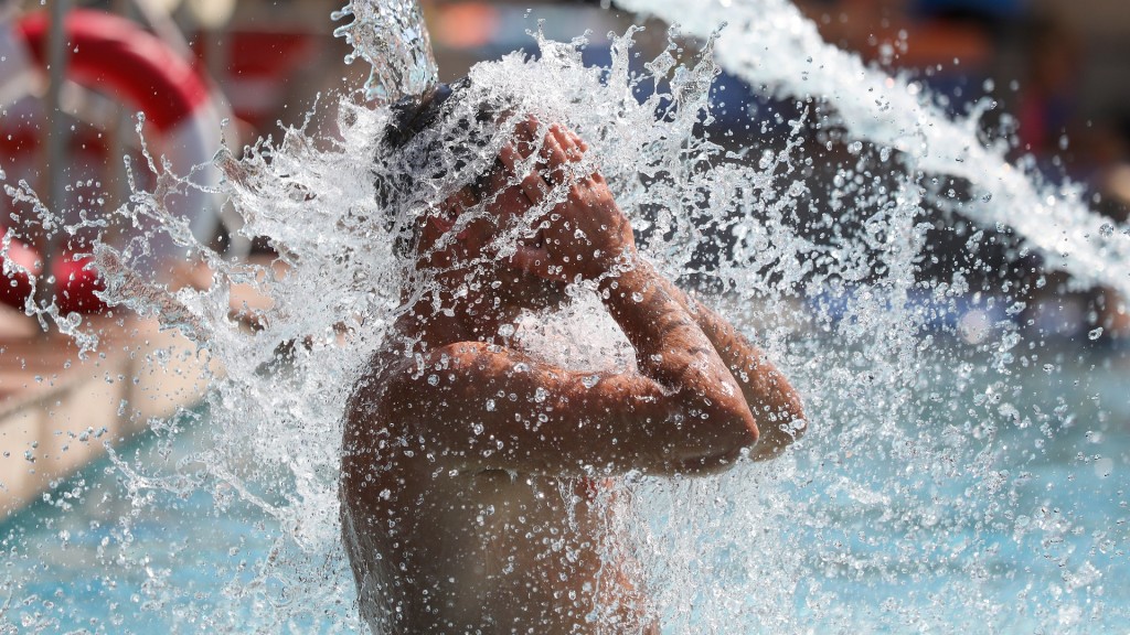 Ein Mann kühlt sich im Freibad ab.