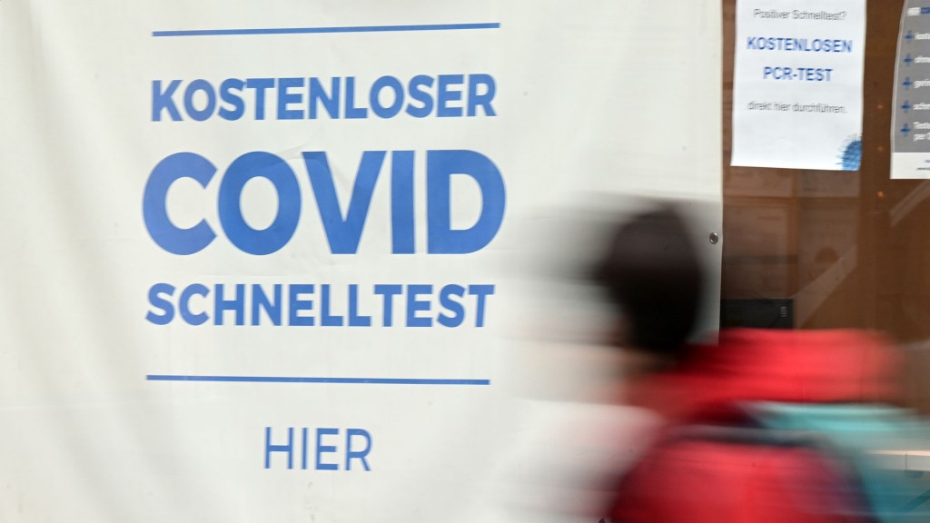 Eine Person läuft am Schild einer Covid-Test-Stelle vorbei