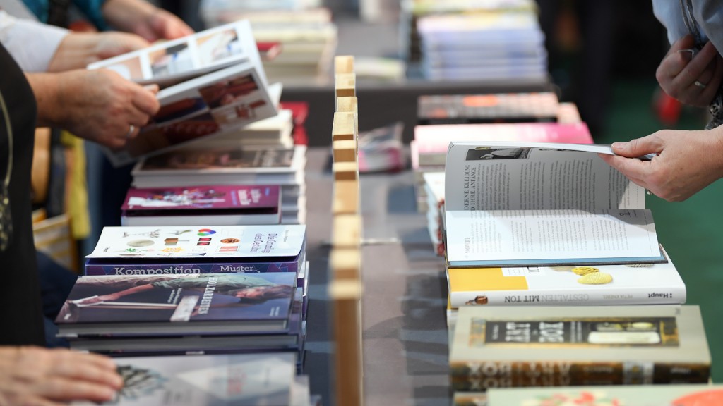 Besucher einer Buchmesse blättern am Verlagsstand in Büchern