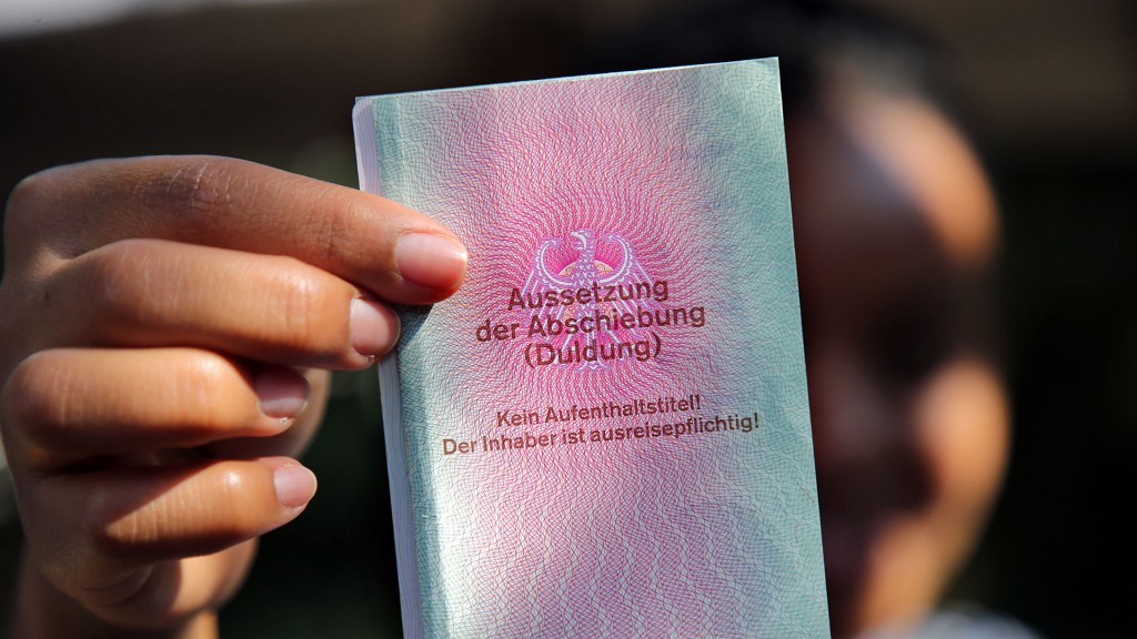 Eine junge Frau hält einen Ausweis für Geflüchtete in der Hand mit dem Titel: Aussetzung der Abschiebung (Duldung)