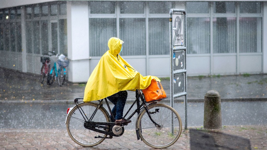 Eine Radfahrerin schützt sich mit einem gelbem Regenponcho gegen eine häftigen Schauer