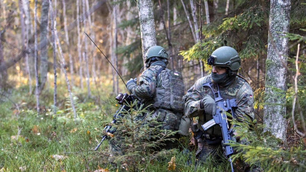 Soldaten der Bundeswehr hocken bei einer Übung in einem Waldstück.