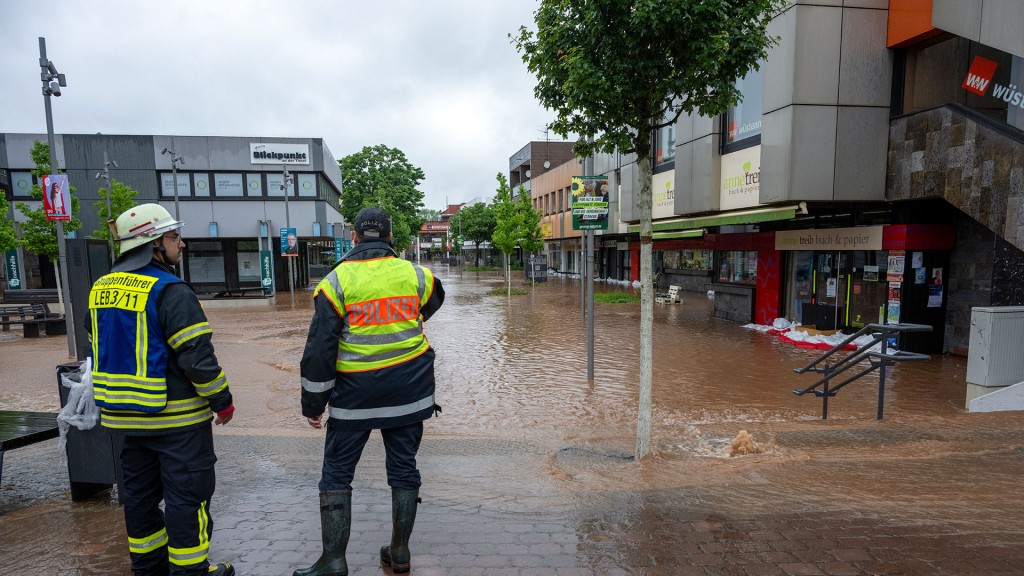 Ein Feuerwehrmann und ein Polizist stehen in der überfluteten Innenstadt von Lebach