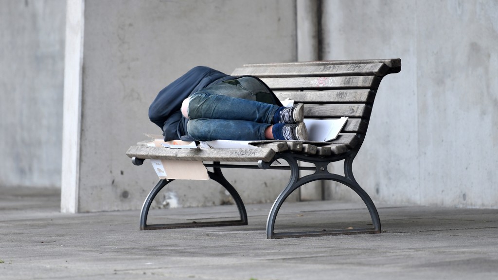 Foto: Eine Person schläft auf einer Bank.