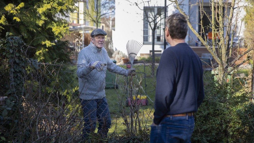 Zwei Männer unterhalten sich am Gartenzaun