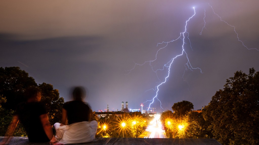 Zwei Personen beobachten bei Gewitter einen Blitz am Himmel über der Stadt