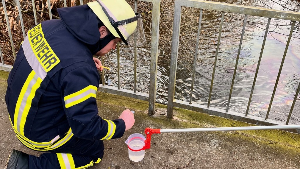 Foto: Ein Feuerwehrmann entnimmt eine Wasserprobe