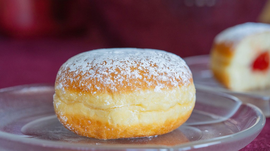 Ein Berliner Krapfen mit Puderzucker im Vordergrund, im Hintergrund aufgeschnitten