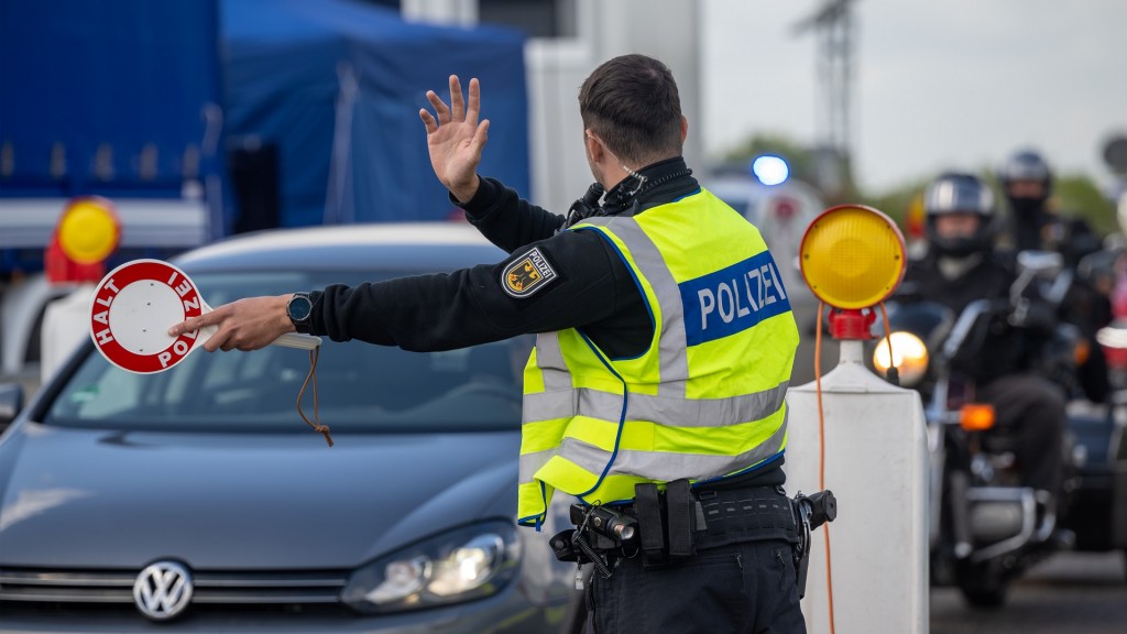 Ein Bundespolizist winkt bei einer Grenzkontrolle Fahrzeuge raus.