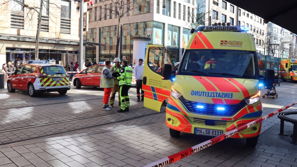 Rettungskräfte stehen bei einem Großeinsatz der Polizei in der Innenstadt von Mannheim.