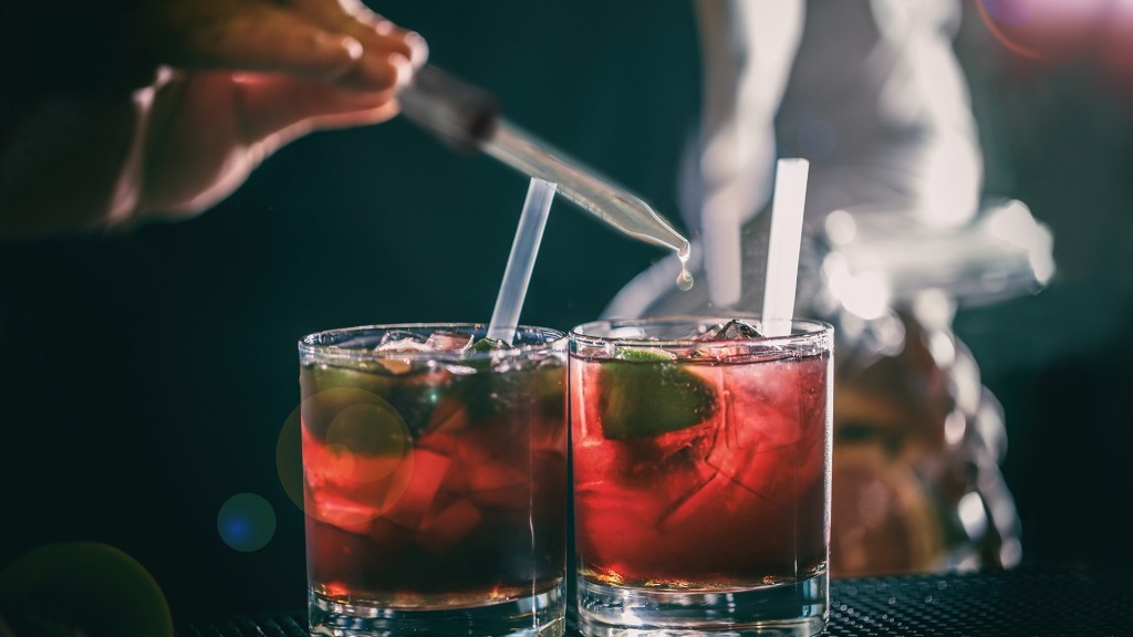 Jemand lässt KO-Tropfen in ein Cocktail-Glas fallen