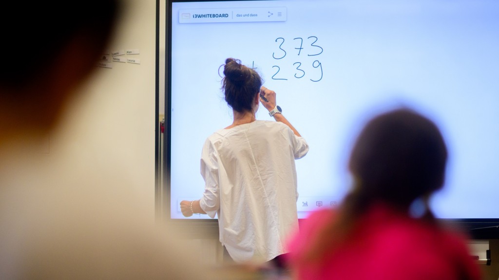 Ein Lehrerin schreibt Zahlen auf eine digitale Schultafel im Klassenraum 