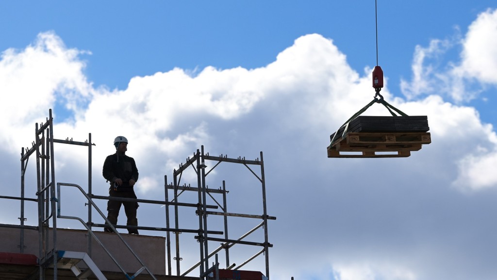 Foto: Ein Arbeiter dirigiert auf einer Baustelle einen Kran. 