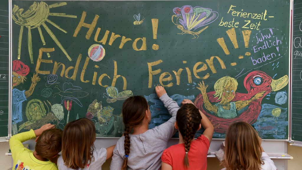Schüler malen Ferienmotive und Wünsche zum Start der Sommerferien auf eine Schultafel.