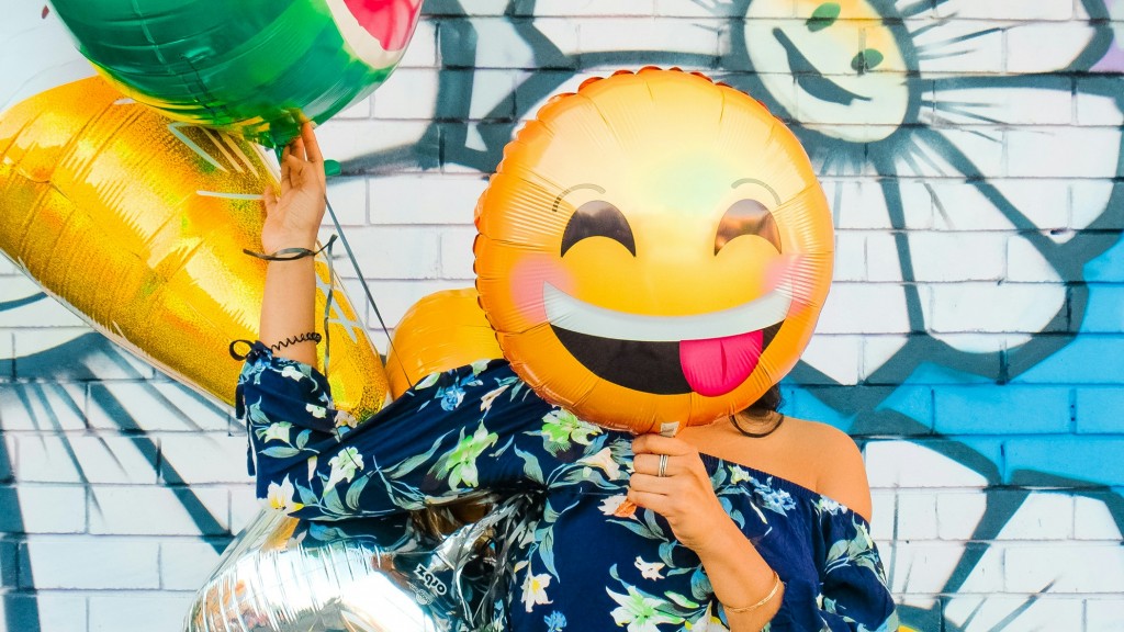 Frau hält einen Emoji-Luftballon vor das Gesicht