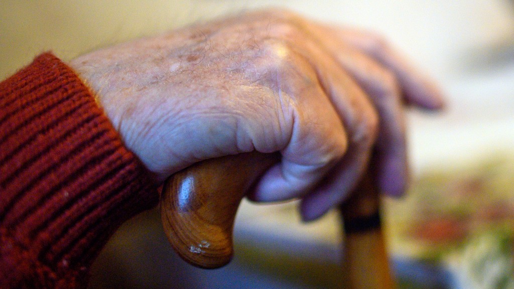 Foto: Eine ältere Person sitzt mit einem Gehstock an einem Tisch