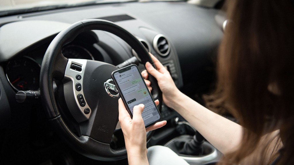 Gestellte Szene: Eine Frau schreibt am Smartphone beim Autofahren