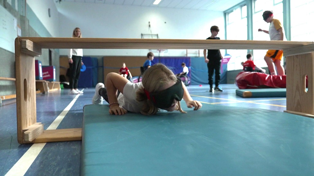 Kind mit Augenbinde klettert durch einen Kasten