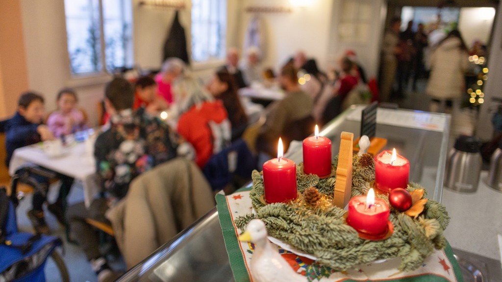 Vier Kerzen brennen an einem Adventskranz bei der Weihnachtsfeier für Bedürftige.