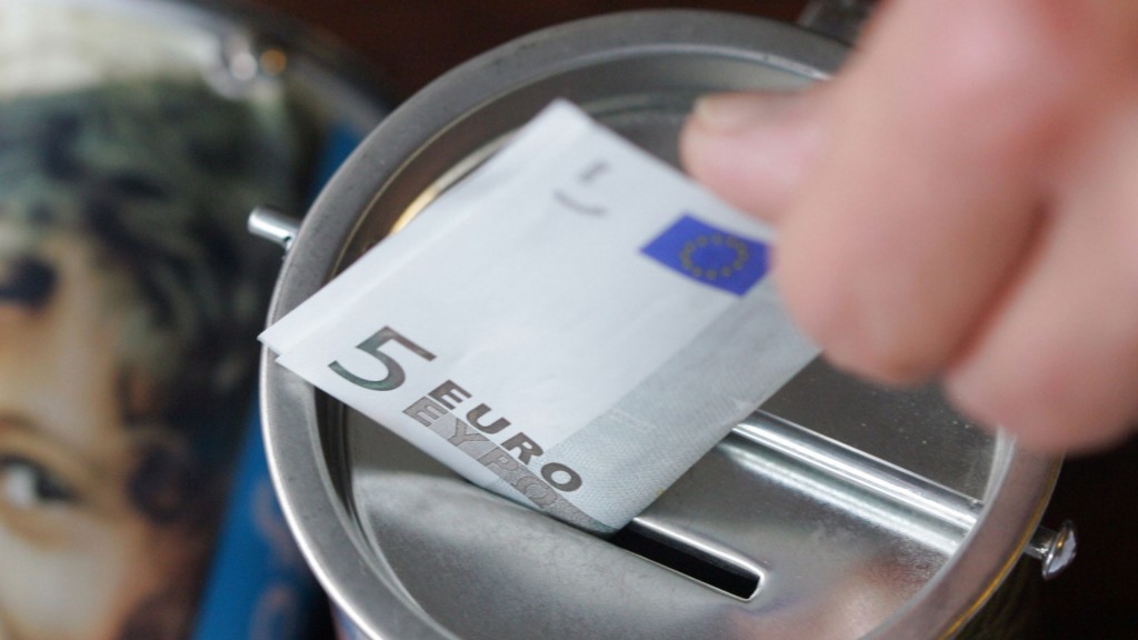 Ein Geldschein wird in eine Spendendose gesteckt